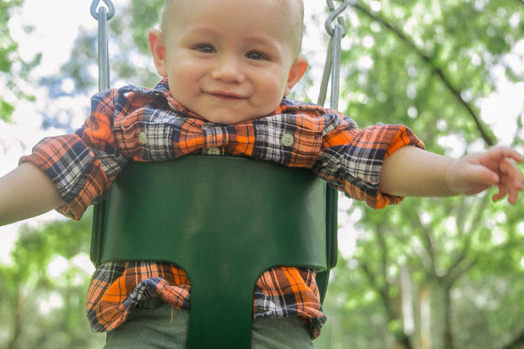 Close-up portrait of cute boy in swing at park