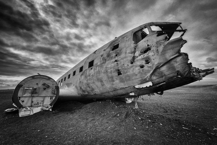 Damaged airplane on land against sky