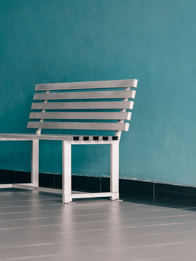 Empty bench by against blue wall