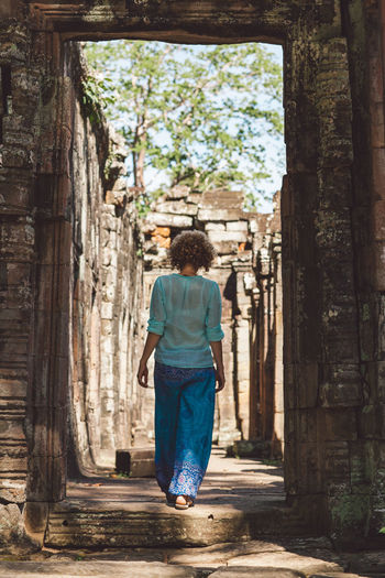 Rear view of woman walking in old corridor 