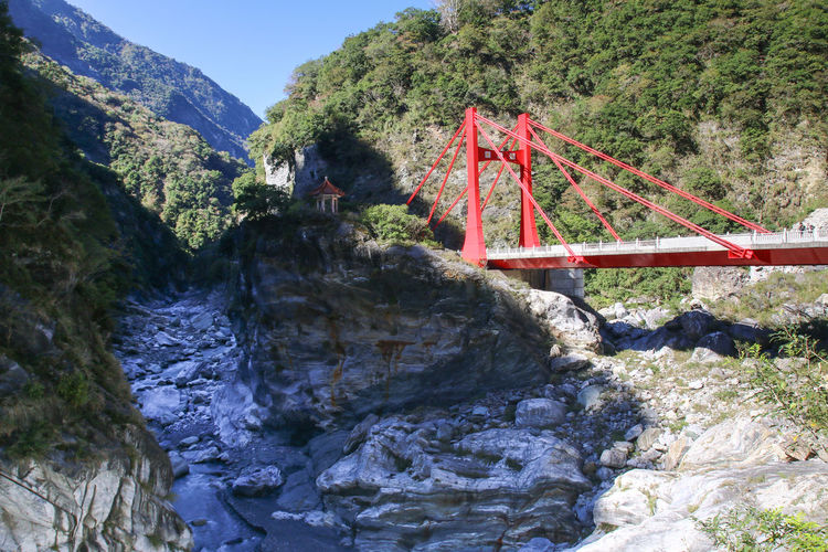 Bridge over rocks against trees and mountains