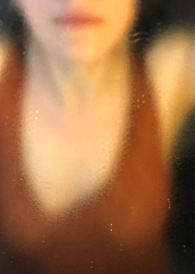 Close-up of woman seen through wet glass