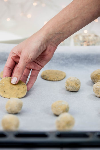 Cropped hand preparing cookies on baking sheet