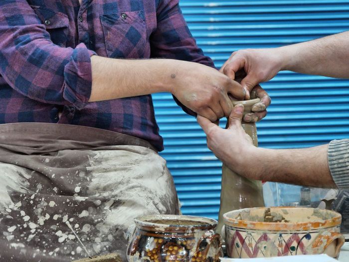 Midsection of man with coworker making earthenware