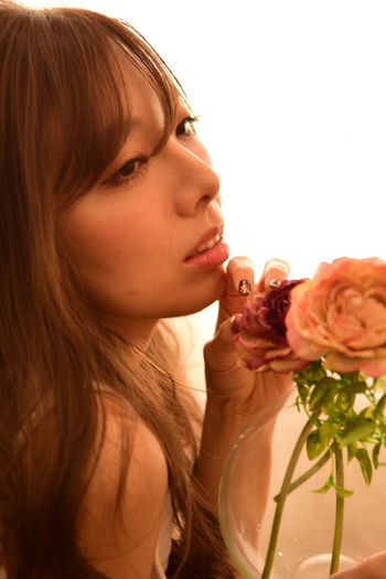 Close-up of young woman holding rose at home