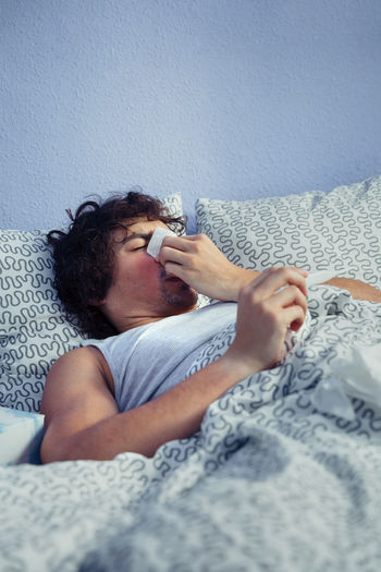 Young man with flu on bed at home