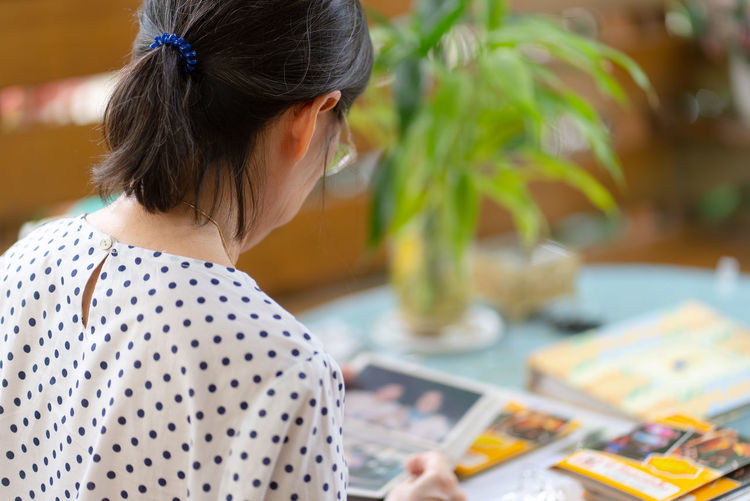 Senior asian woman looking at photo album to remind of old happy memory
