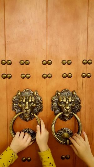 Cropped hands holding metallic door knockers