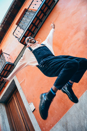 Low angle view of young man jumping against wall