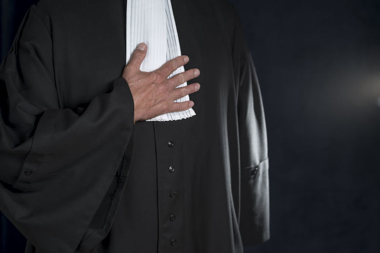 Midsection of judge standing against black background