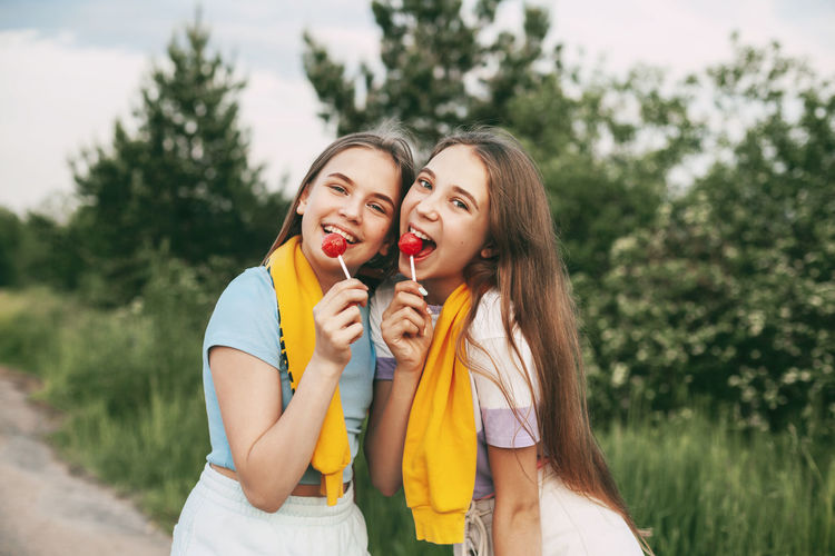Portrait of smiling girls holding lollipop while standing outdoors