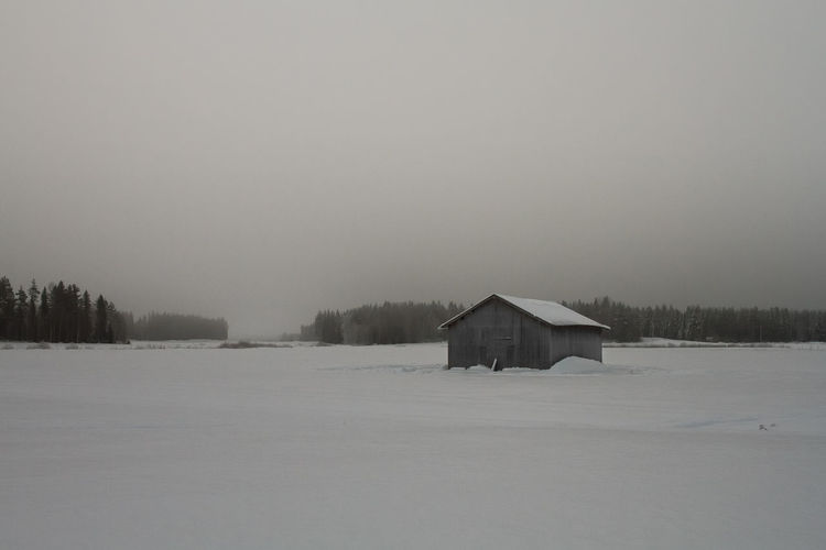 Early winter morning on the snowy fields at the northern finland. mist rises over the barn houses.