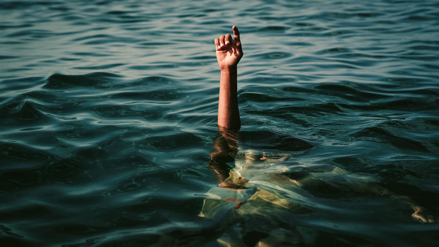 Cropped hand of man swimming underwater