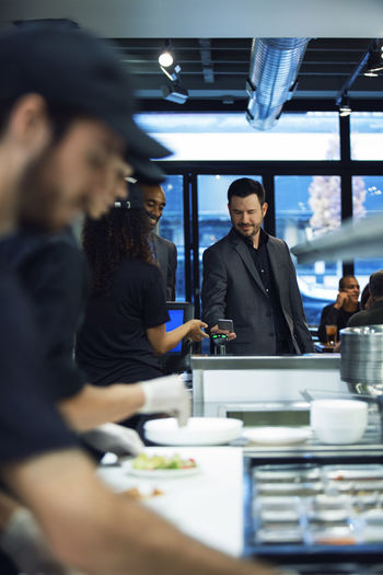 Businessman paying bill through smart phone while standing in restaurant