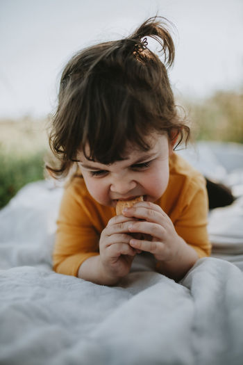 Child lying on the grass eating cookie