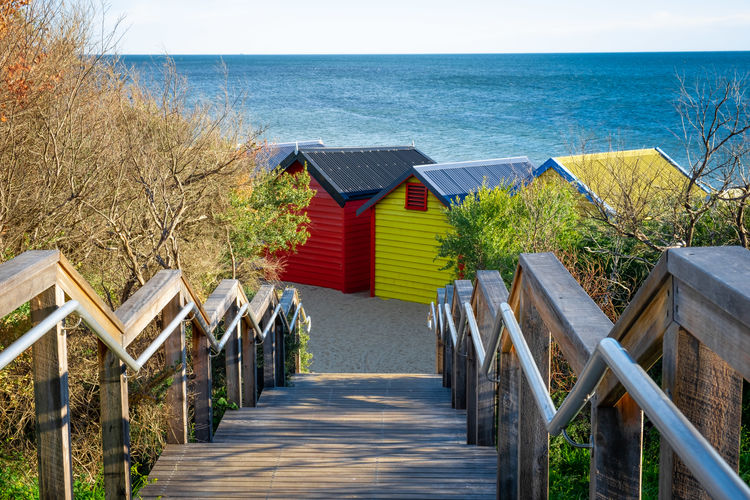Wooden stairs leading down to iconic brighton beach huts on ocean beach in melbourne, australia