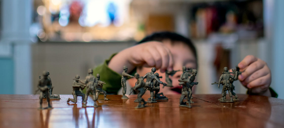 Small hands move toy soldiers around a mock battle on a tabletop