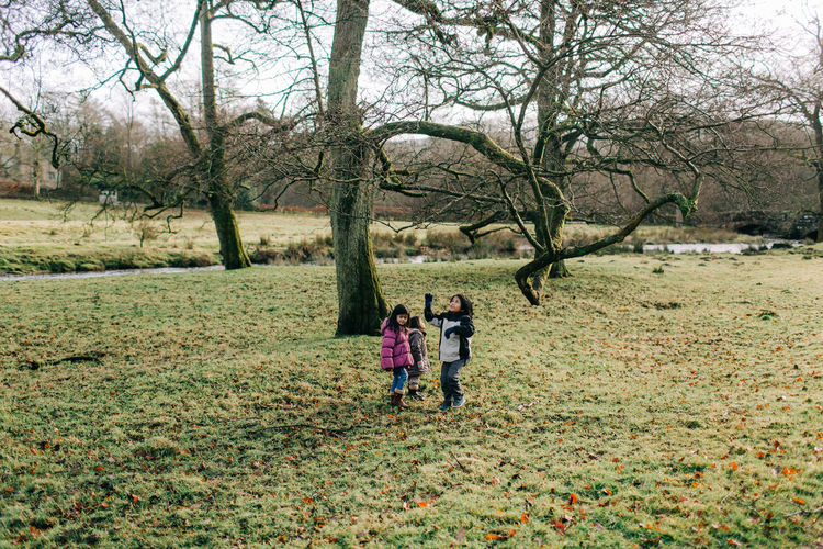 People standing on grassy land against trees