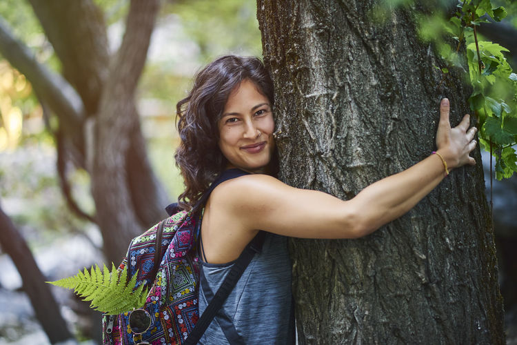 Young woman hugging a tree. she is happy.