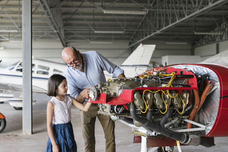Grandfather showing how to fix airplane tool to granddaughter