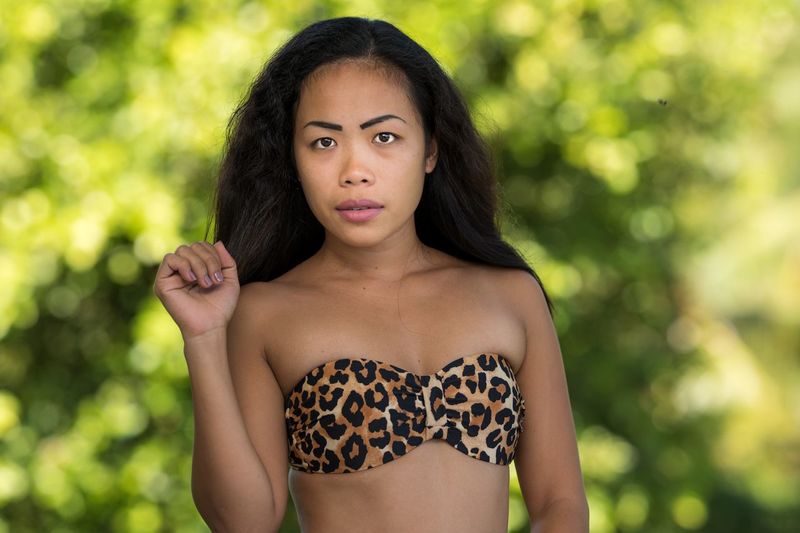 Woman in bikini top standing outdoors