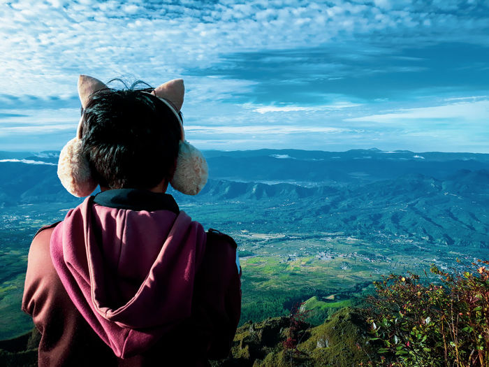 Rear view of man wearing ear puff against landscape