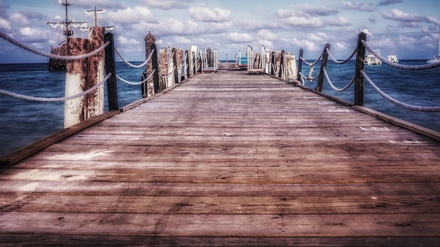 Wooden pier in sea against sky