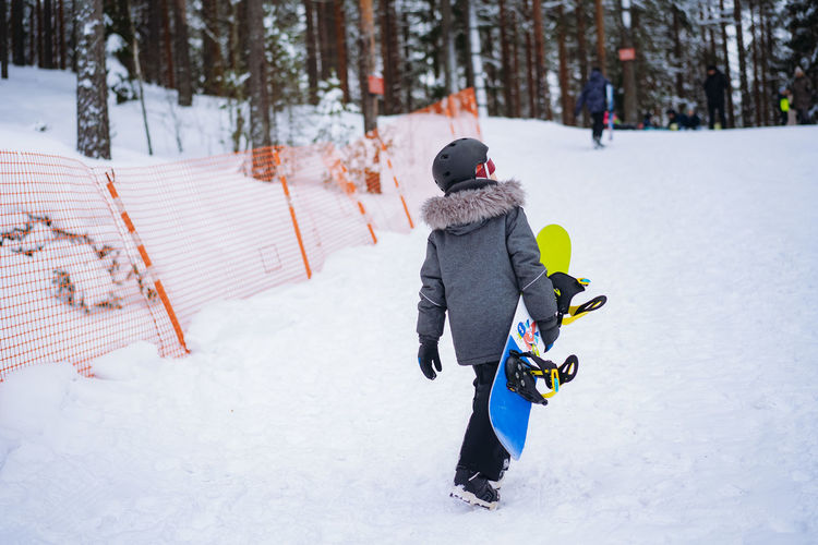 Little boy learning to ride on snowboard