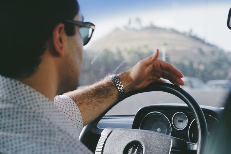 Cropped image of man holding steering wheel in car