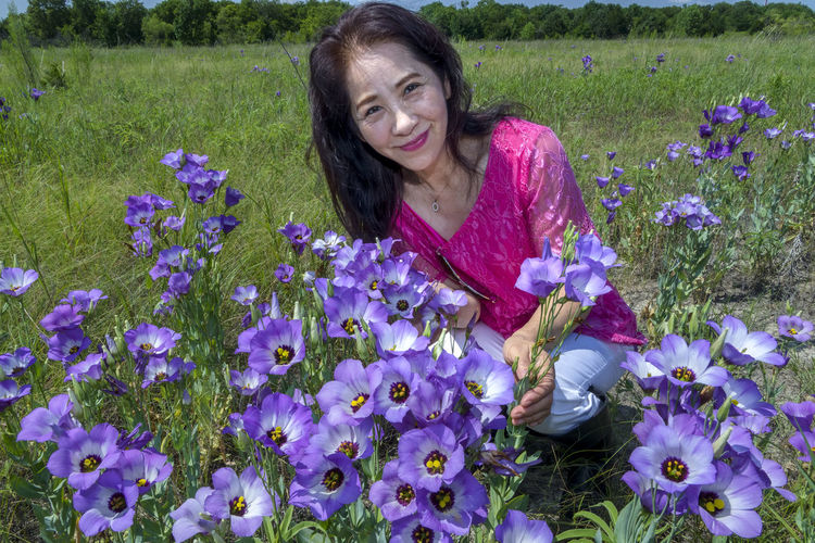 Woman with purple flowers on field