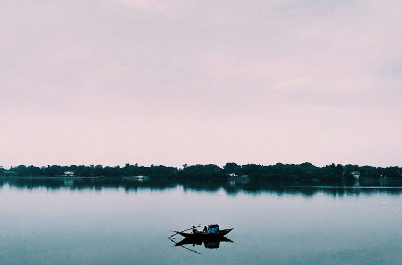 Silhouette of boat in lake against sky during sunset