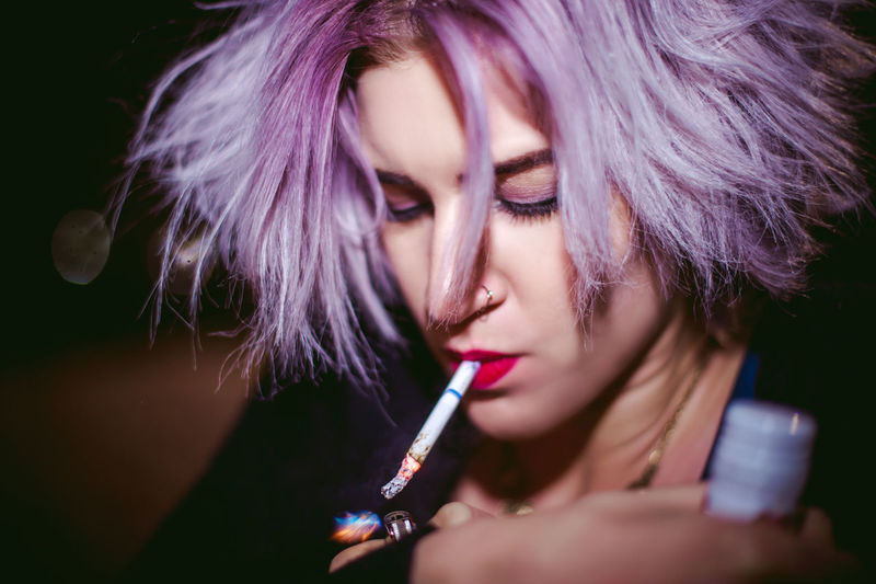 Portrait of beautiful young woman smoking cigarette