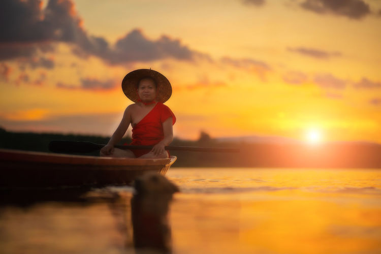 Full length of boy enjoying in sea against sky during sunset