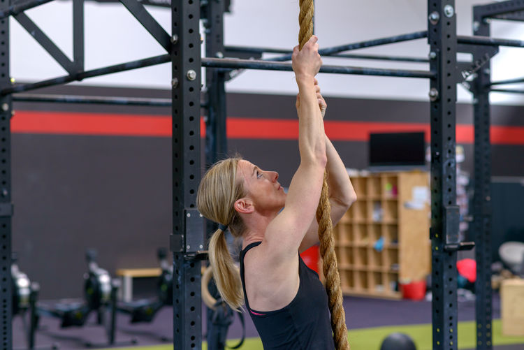 Woman climbing rope at gym