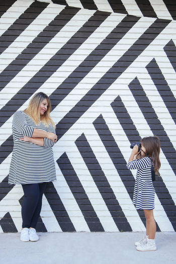 Full length of woman standing against wall