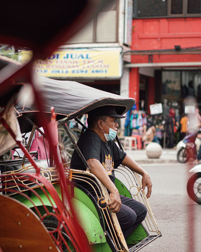 Man wearing mask sitting in jinrikisha