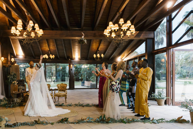 Bride throwing bouquet toward friends standing behind at banquet
