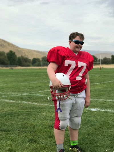 Boy wearing american football uniform on playing field