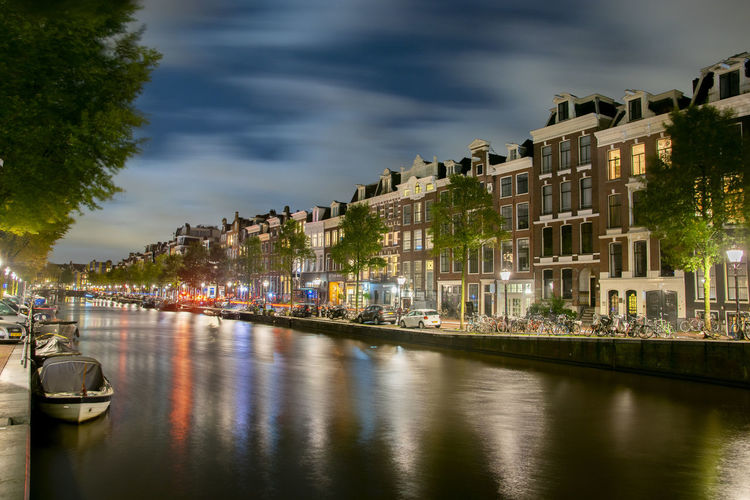 Panoramic view of river amidst buildings in city at night