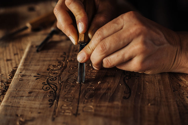 Close up process of decorative wood engraving using hand tools