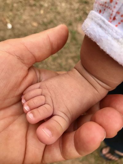 Cropped hand of person holding baby leg