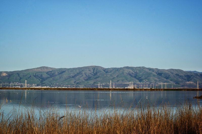Scenic view of lake and mountains against clear blue sky