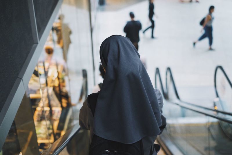 Rear view of a nun on escalator