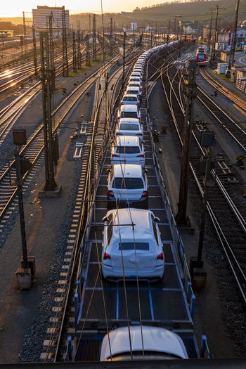 Germany, bavaria, wurzburg, row od cars transported along city railroad tracks at sunset