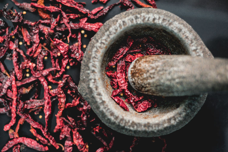 Directly above shot of mortar and pestle by dry red chili peppers
