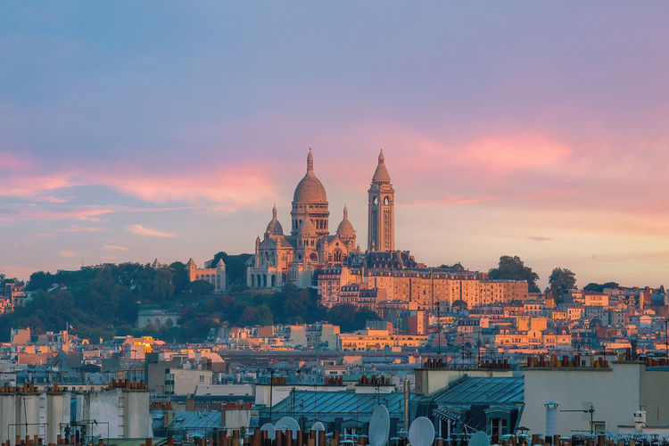 Buildings in city against sky during sunset