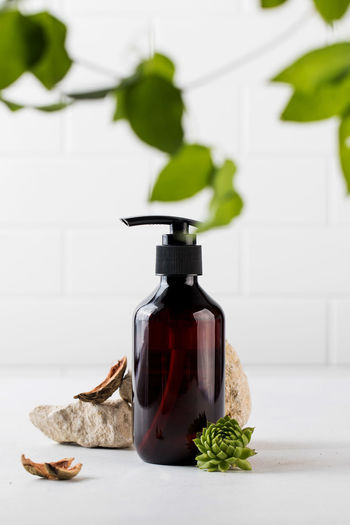 Organic cosmetic product in a brown dispenser surrounded by natural materials. 