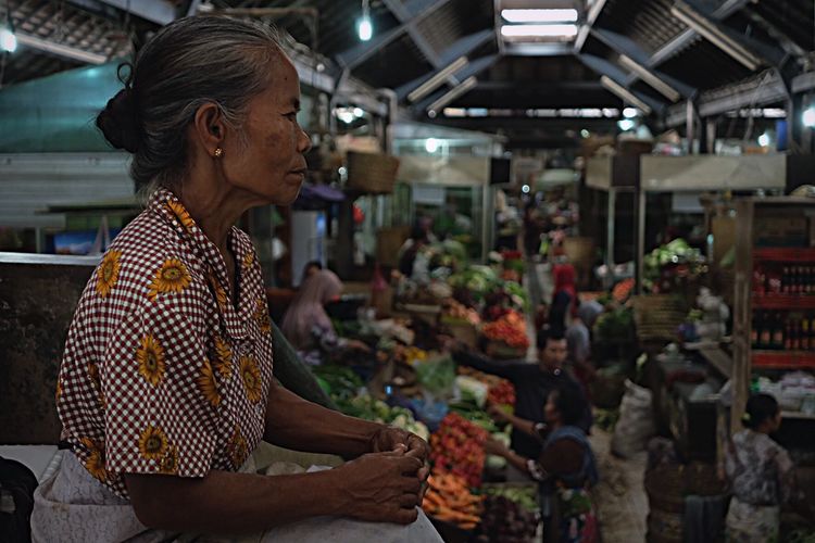 Side view of senior woman in market at night
