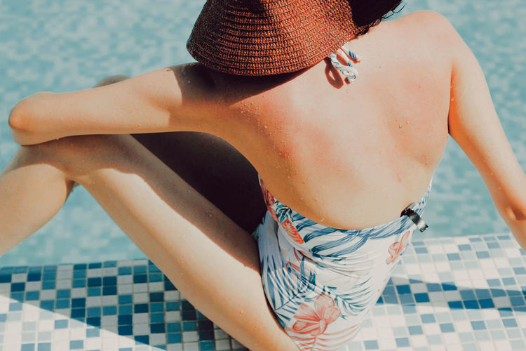 Midsection of woman relaxing on swimming pool
