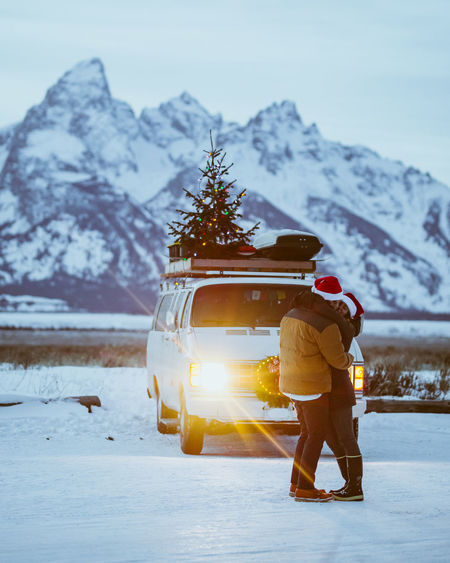 Couple kissing in front of their van life with christmas tree christmas tree